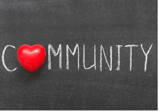 The word 'Community' written out on a chalk board with a red heart in place of the letter '