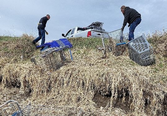 Code Enforcement officers clear shopping carts away from the ditch. 