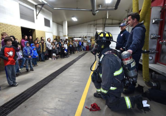 Children take a tour of a fire station. 